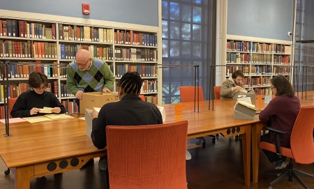 Five people at a long table do book research.